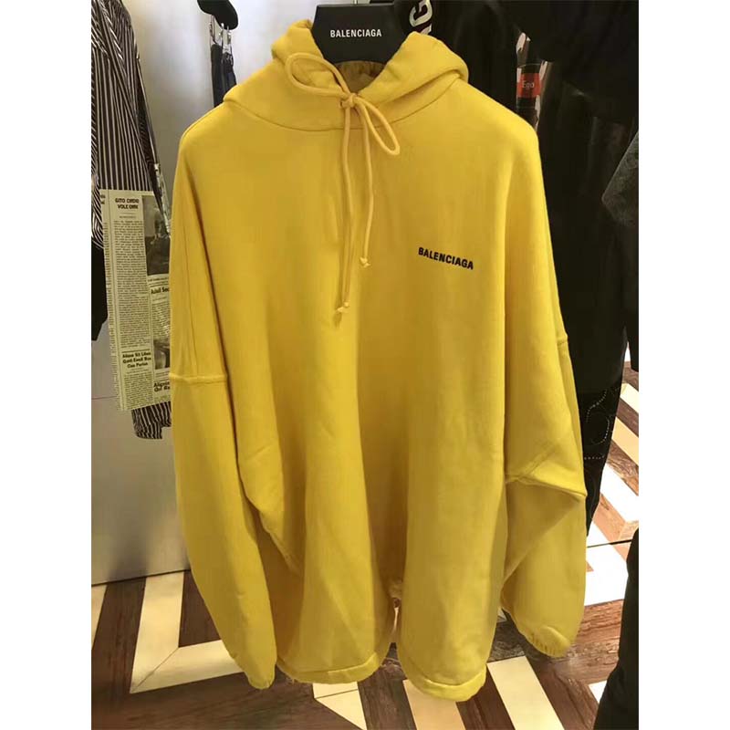 Close-up of Balenciaga logo print on yellow hooded sweater cardigan