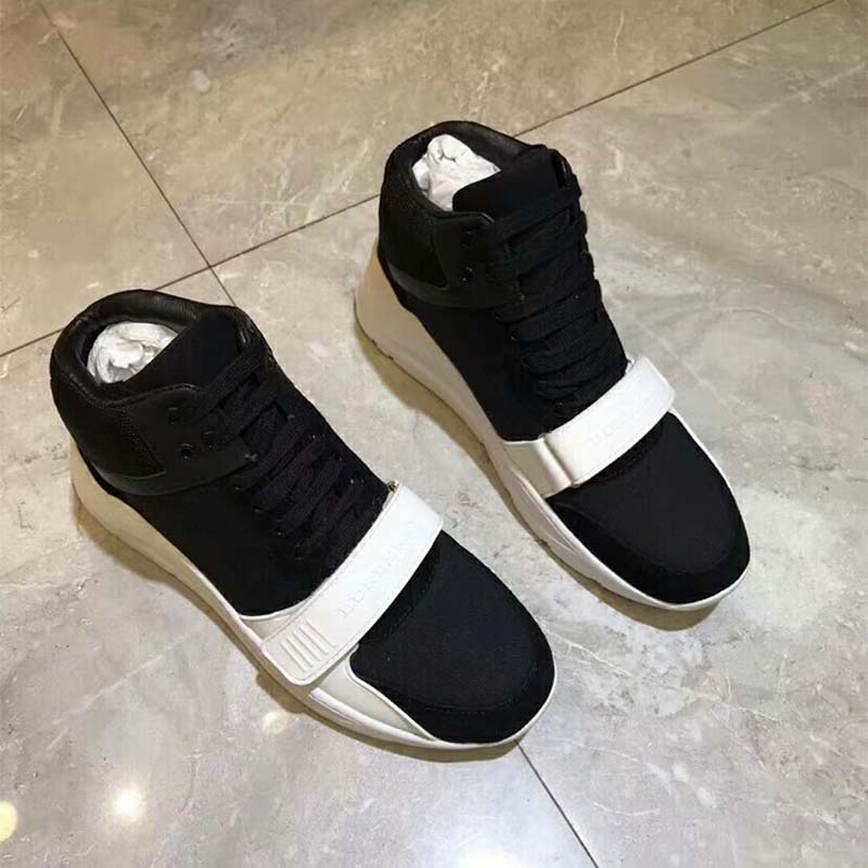Close-up detail of Burberry branding on black high-top sneakers