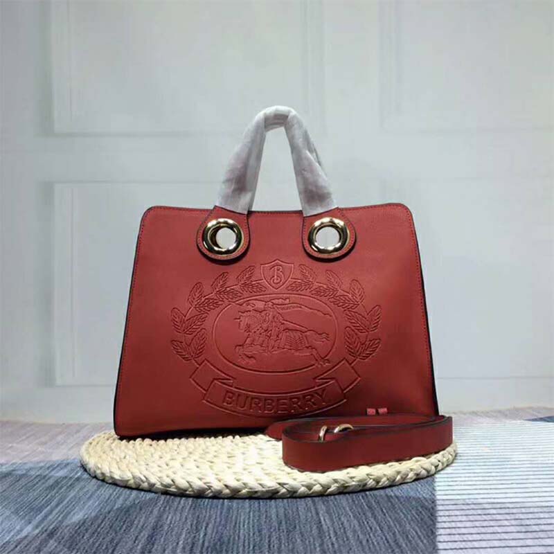 Close-up of signature grommet and crest detail on Burberry tote in red