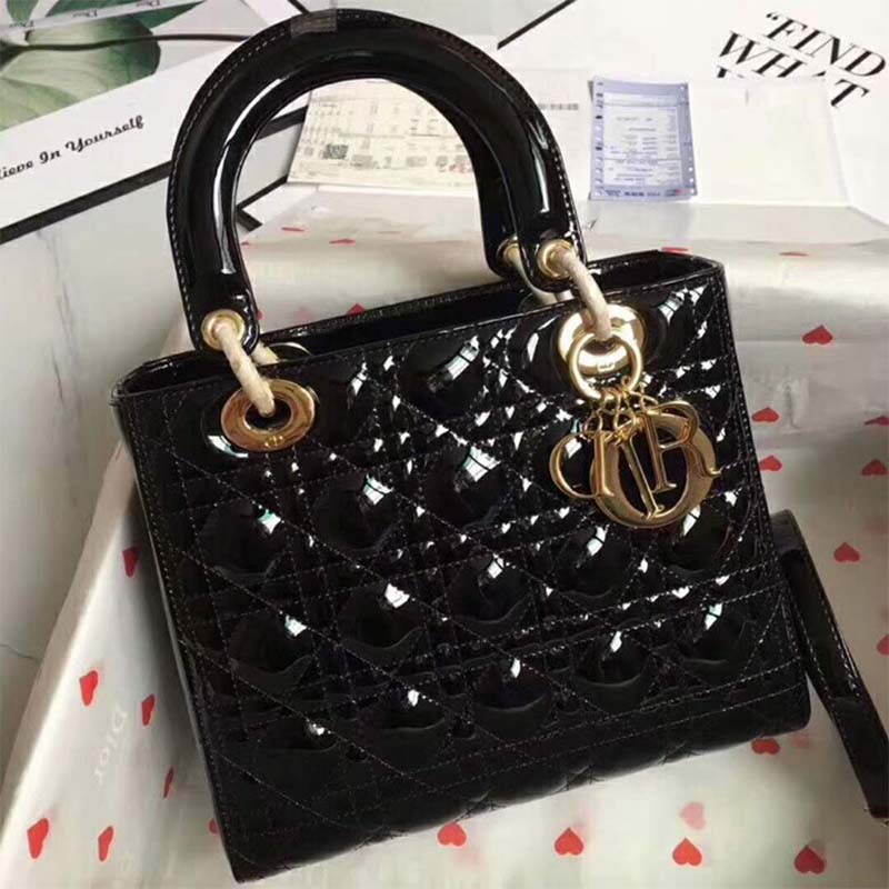 Close-up of gold-tone Dior charms on Lady Dior Bag in Black patent leather