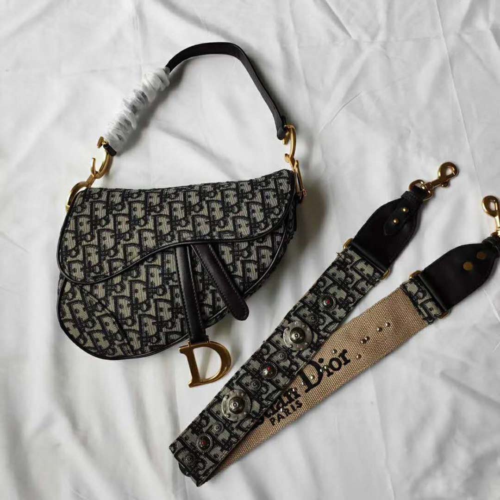 Close-up of navy canvas and antique gold hardware on Dior Oblique Saddle Bag
