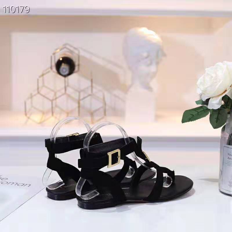 Close-up of polished Double-D logo hardware on black suede sandal