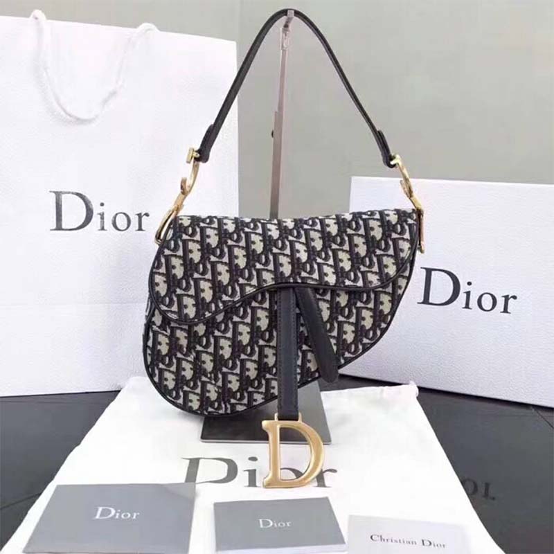 Close-up of gold 'D' charm hardware on Dior Women Saddle Bag