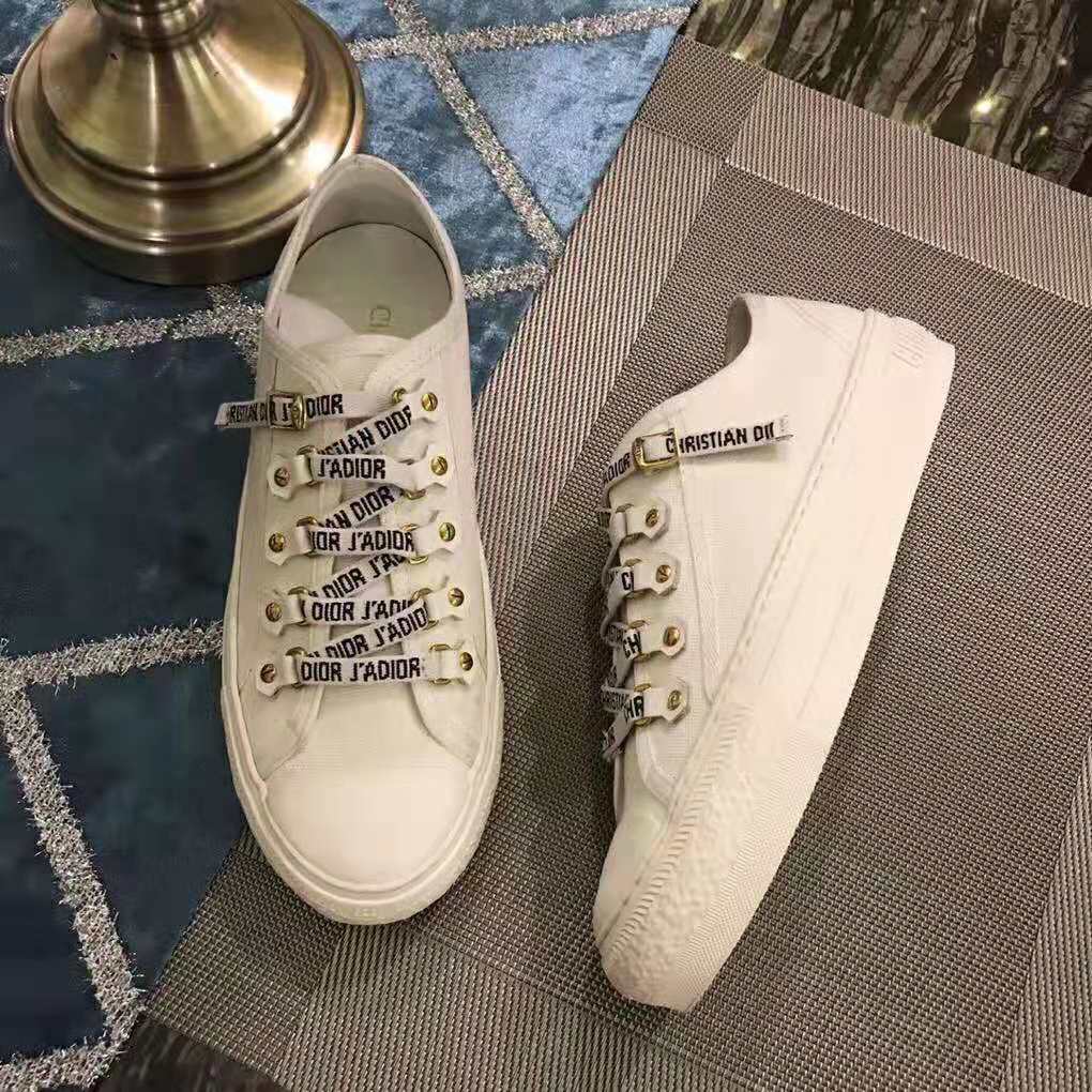 Close-up detail of embroidered Dior logo on white canvas sneaker