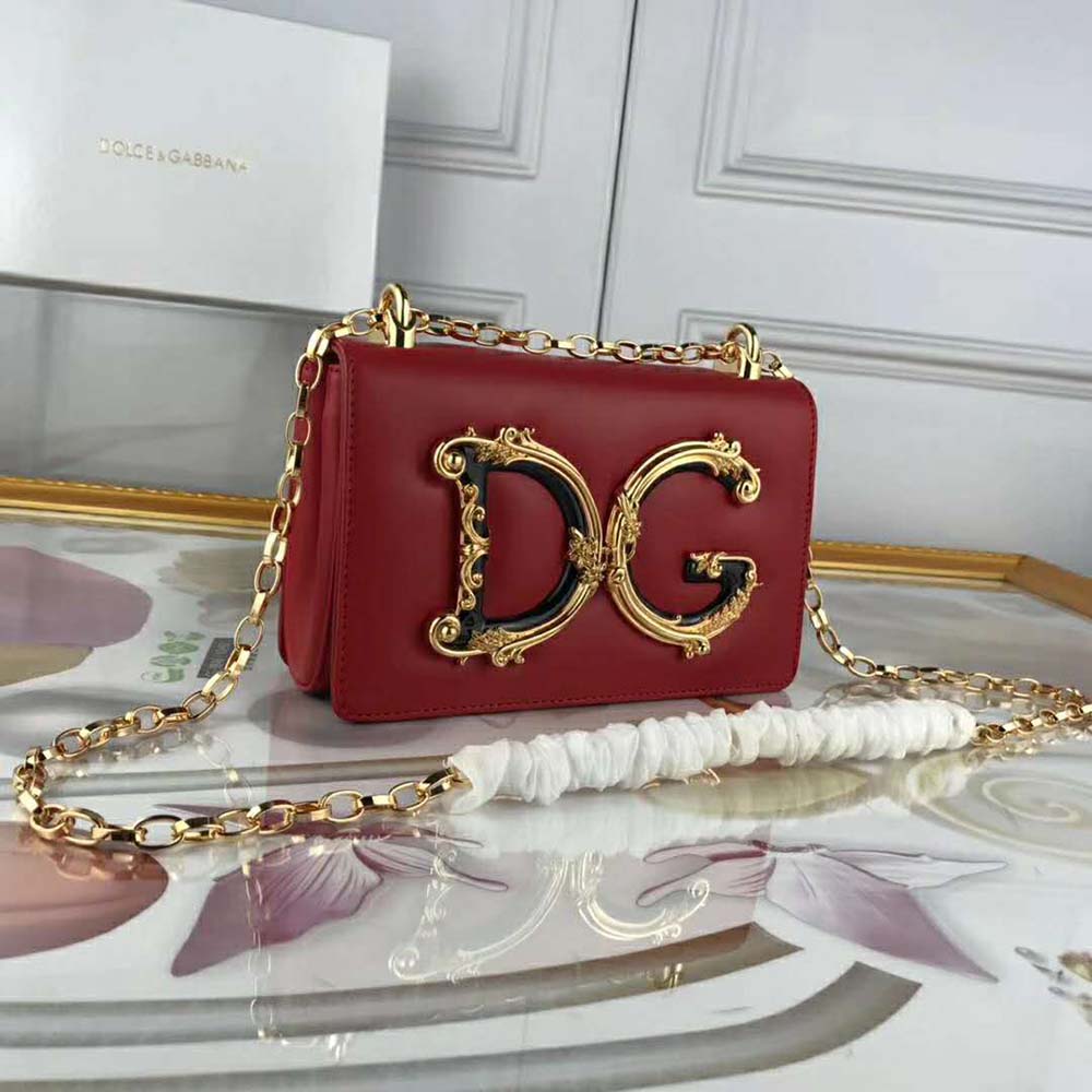 Close-up detail of gold-tone D&G logo on red leather bag