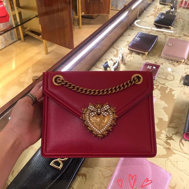 Close-up of gold-tone D&G logo hardware on red leather bag