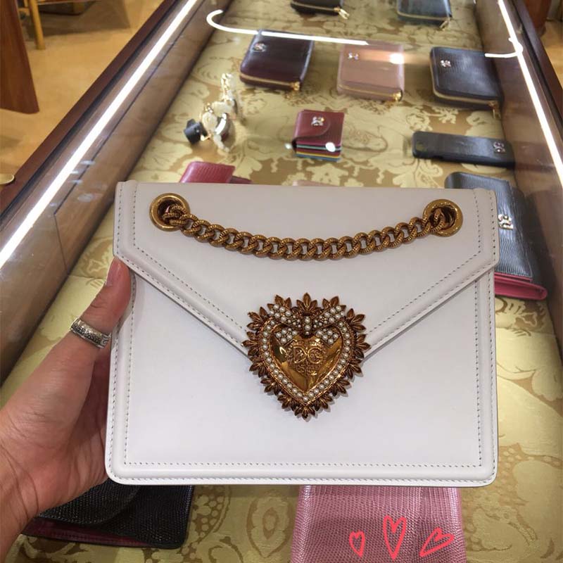 Close-up of gold-tone devotion heart clasp on white D&G medium bag