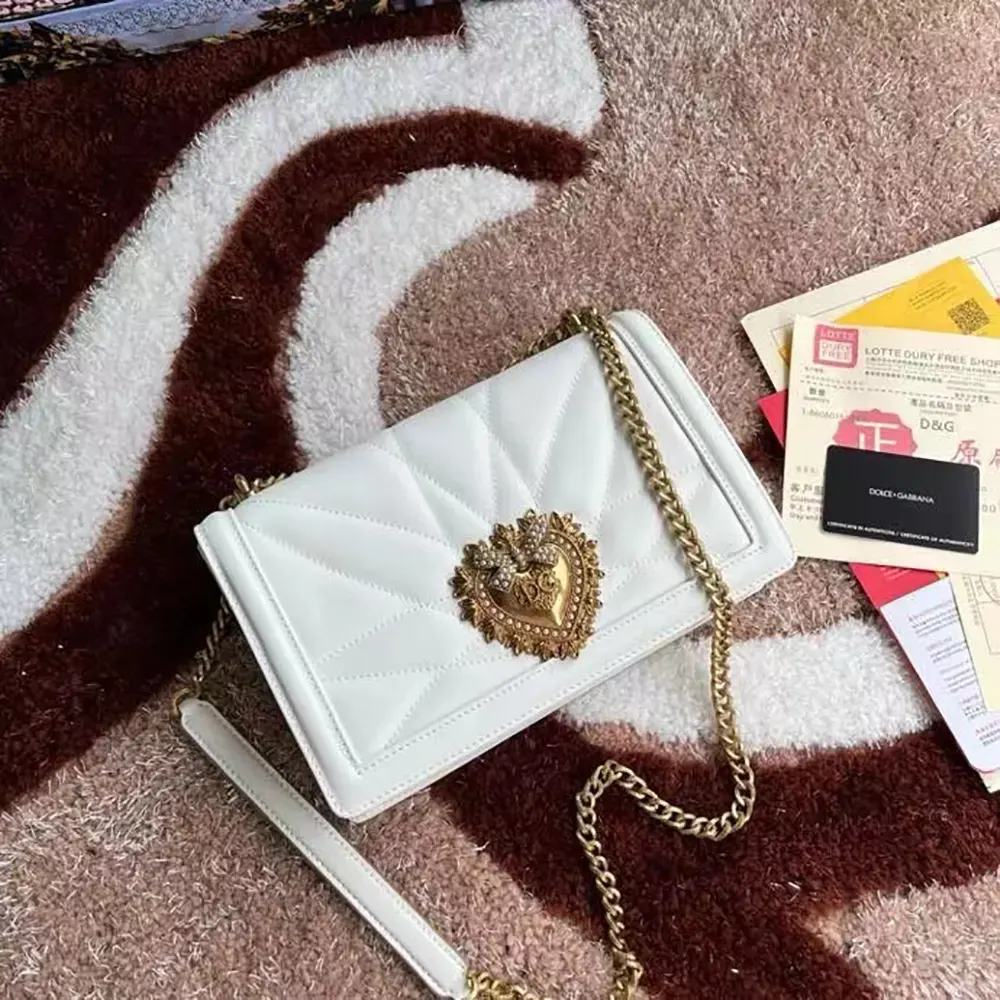 Close-up of gold-tone D&G logo hardware on white quilted bag