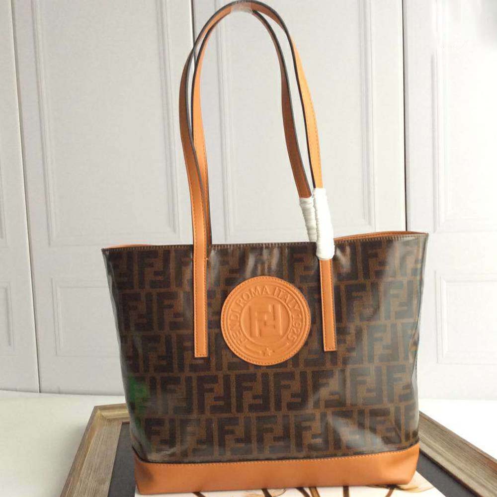 Close-up of gold hardware and signature logo on brown leather shopper
