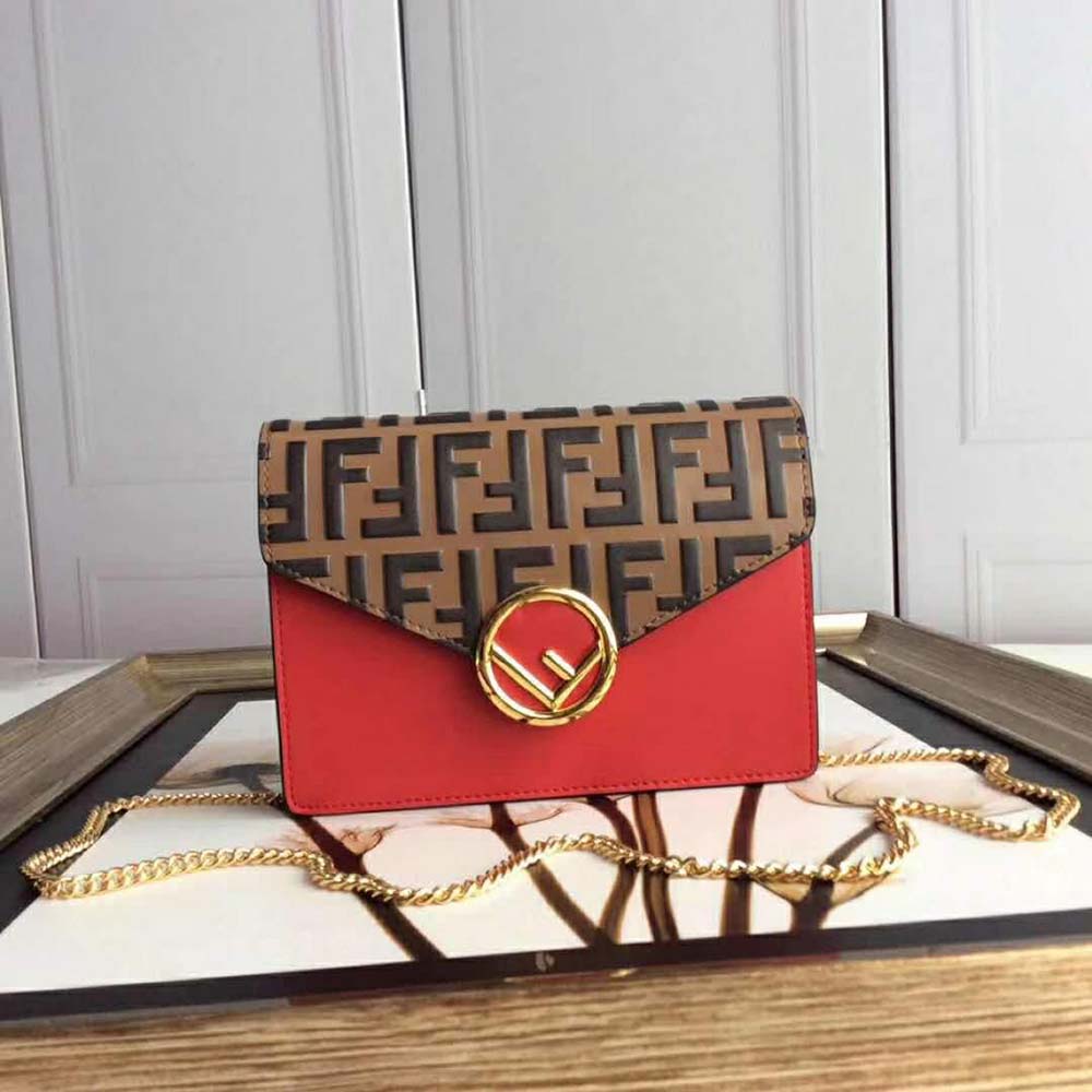 Close-up of gold-tone Fendi logo on red leather mini bag