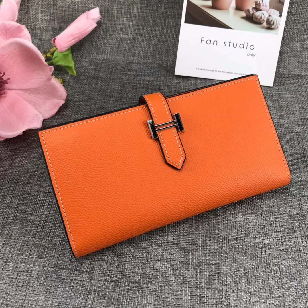 Close-up of orange leather texture and gold hardware on Hermes Medium Bearn Wallet