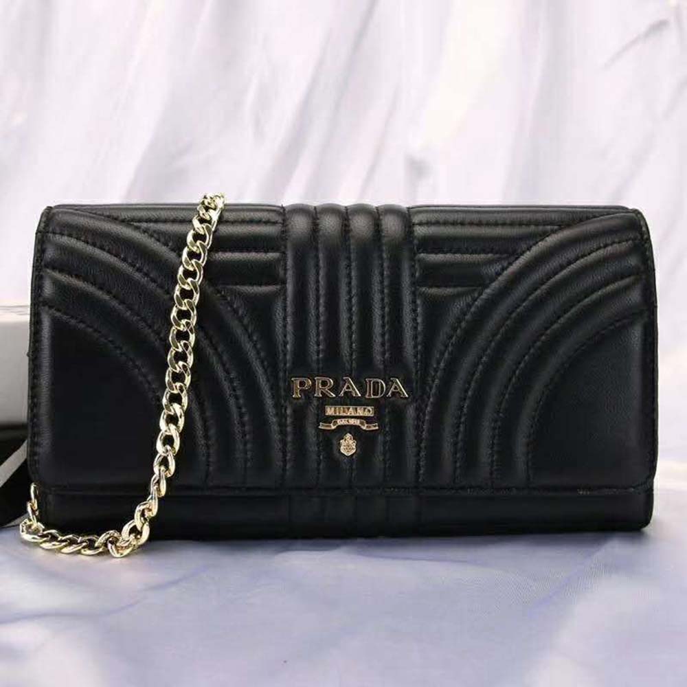 Close-up of Prada triangular logo plaque on black leather mini bag