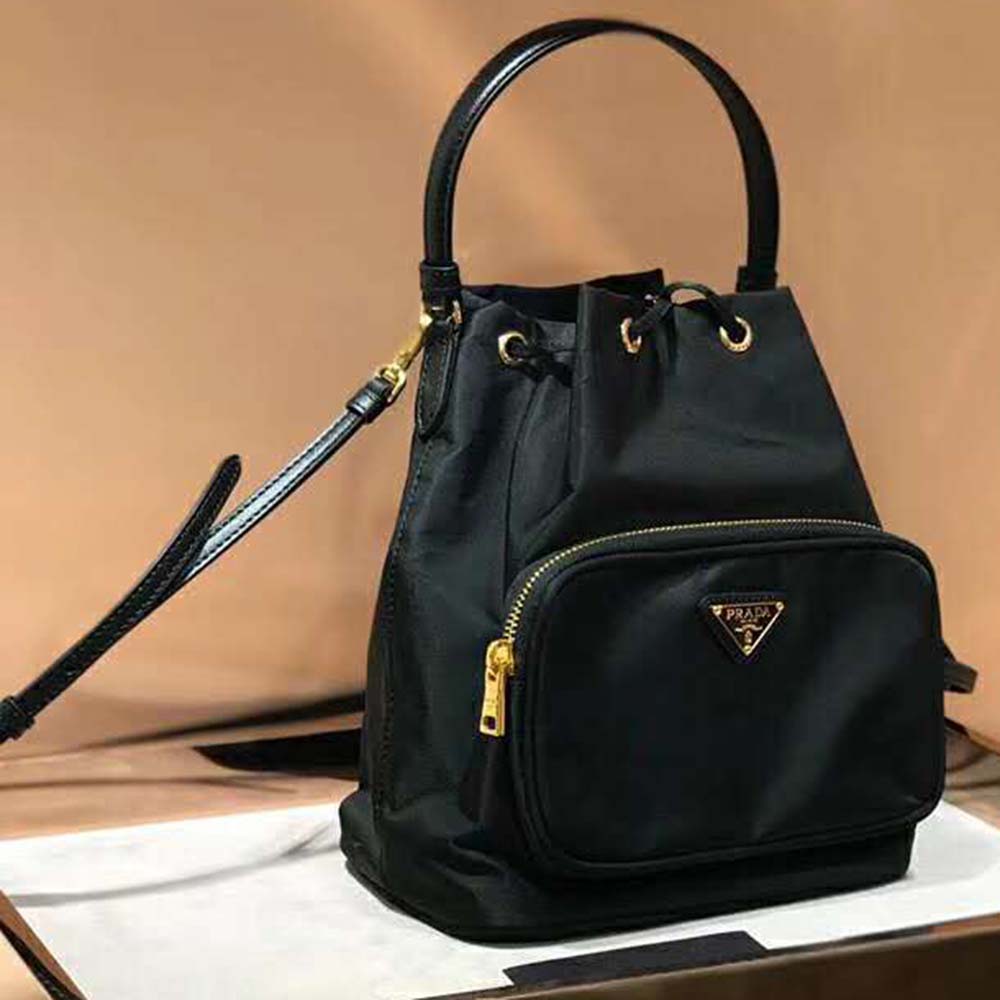 Close-up of silver-tone Prada triangular logo on nylon bag