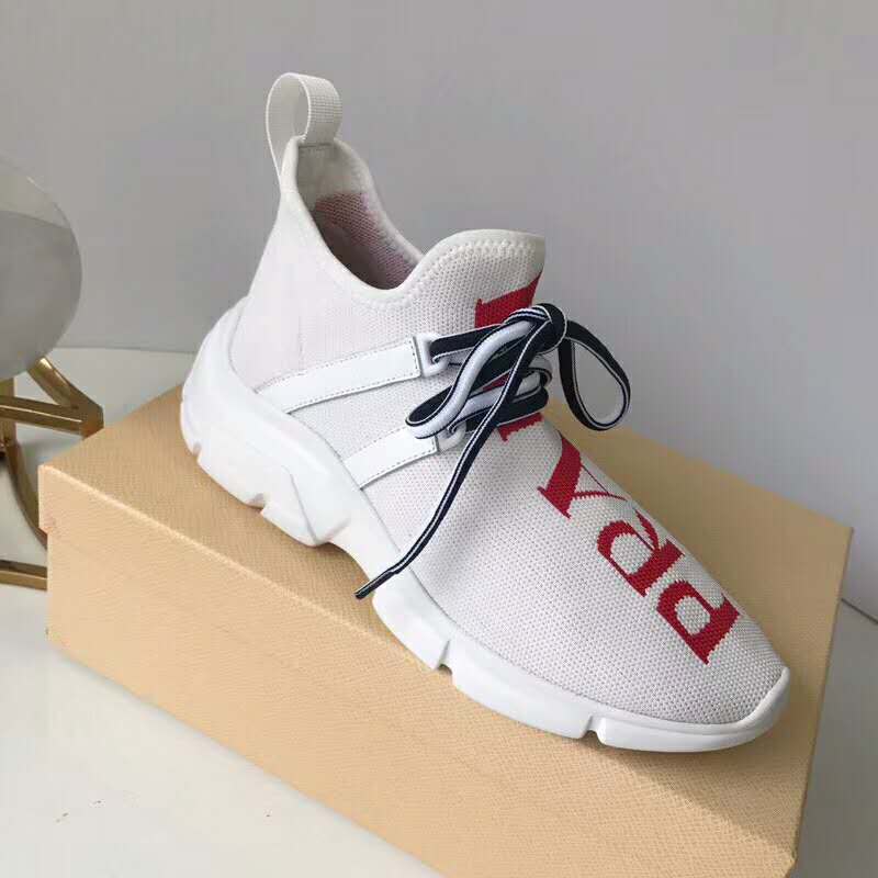 Close-up of knit fabric and Prada branding on the white sneakers