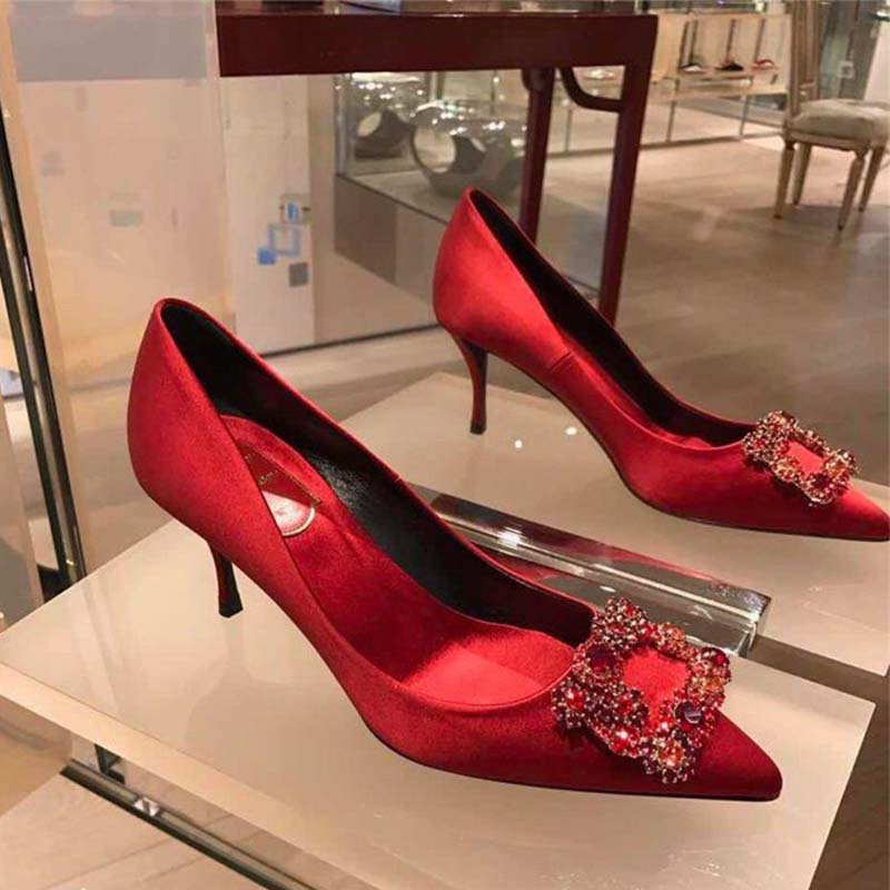 Close-up of signature flower strass buckle on Roger Vivier red pumps