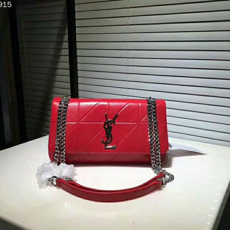 Close-up of gold-tone YSL logo on red patchwork leather bag
