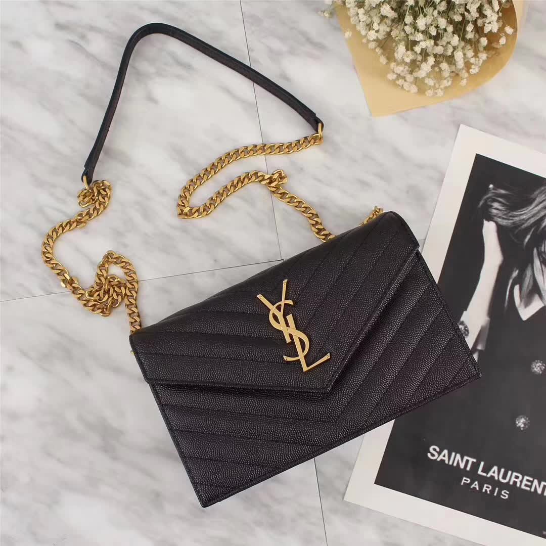 Close-up detail of gold YSL monogram on black leather wallet