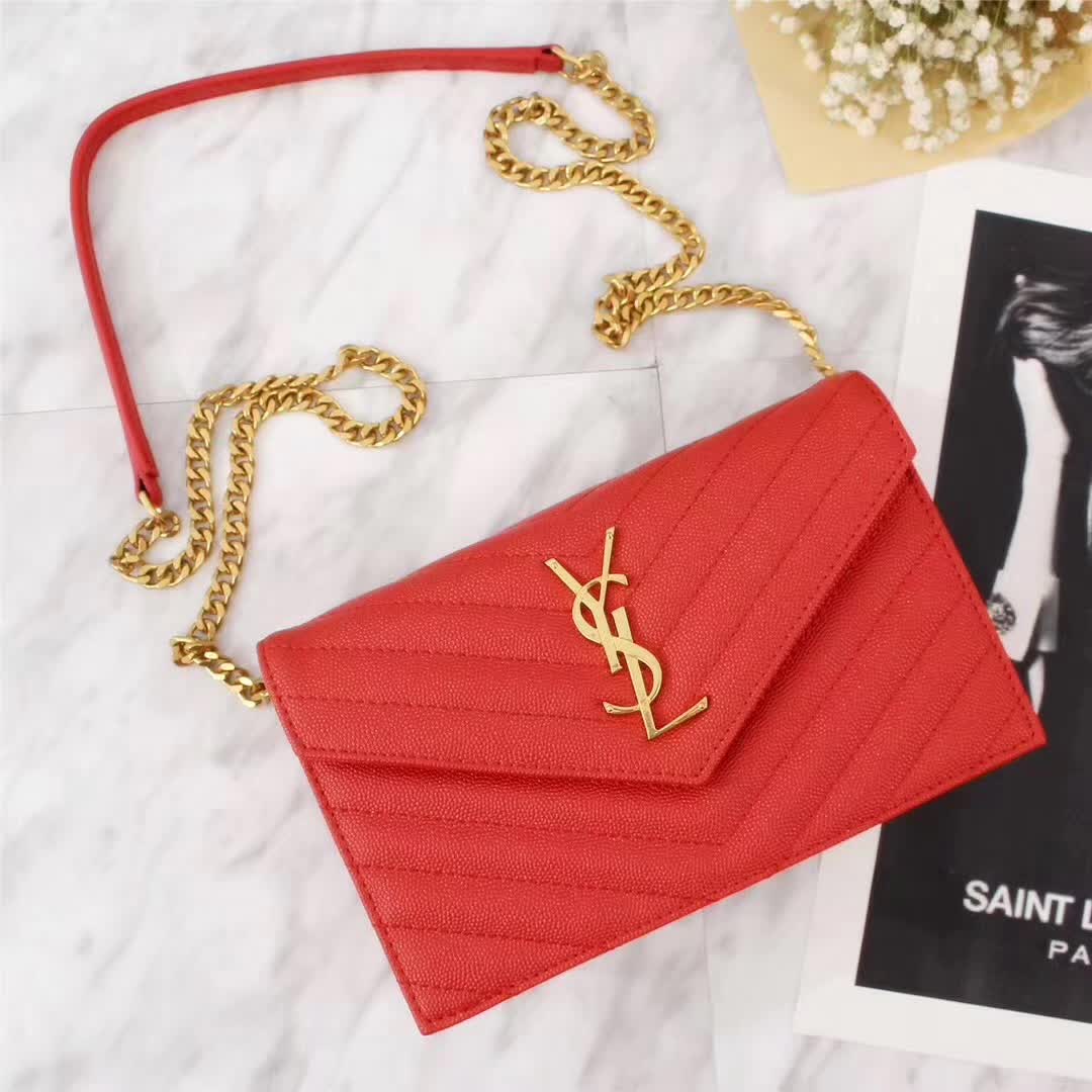 Close-up of gold YSL monogram detail on red leather wallet