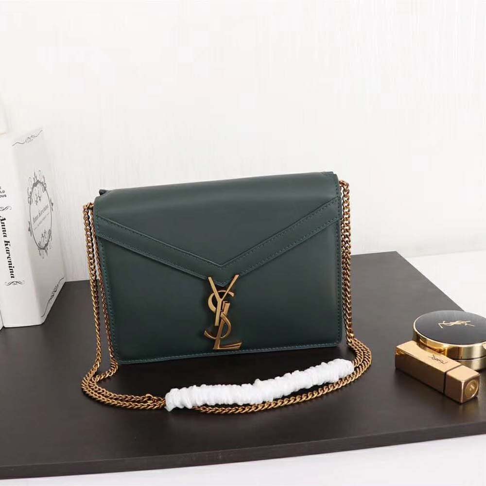 Close-up detail of gold YSL monogram clasp on smooth-green bag