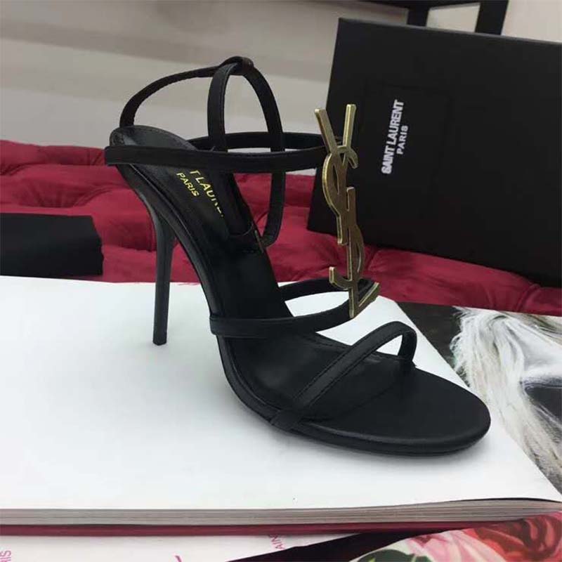Close-up on gold YSL logo hardware of Cassandra Sandal by Saint Laurent
