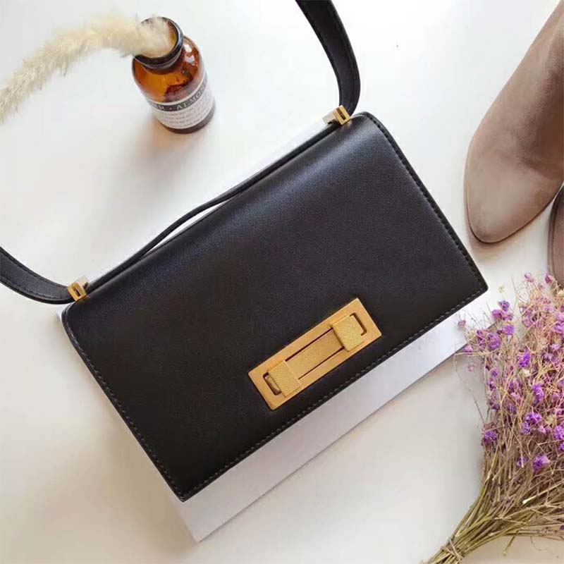 Close-up of gold YSL logo hardware on black leather Domino bag