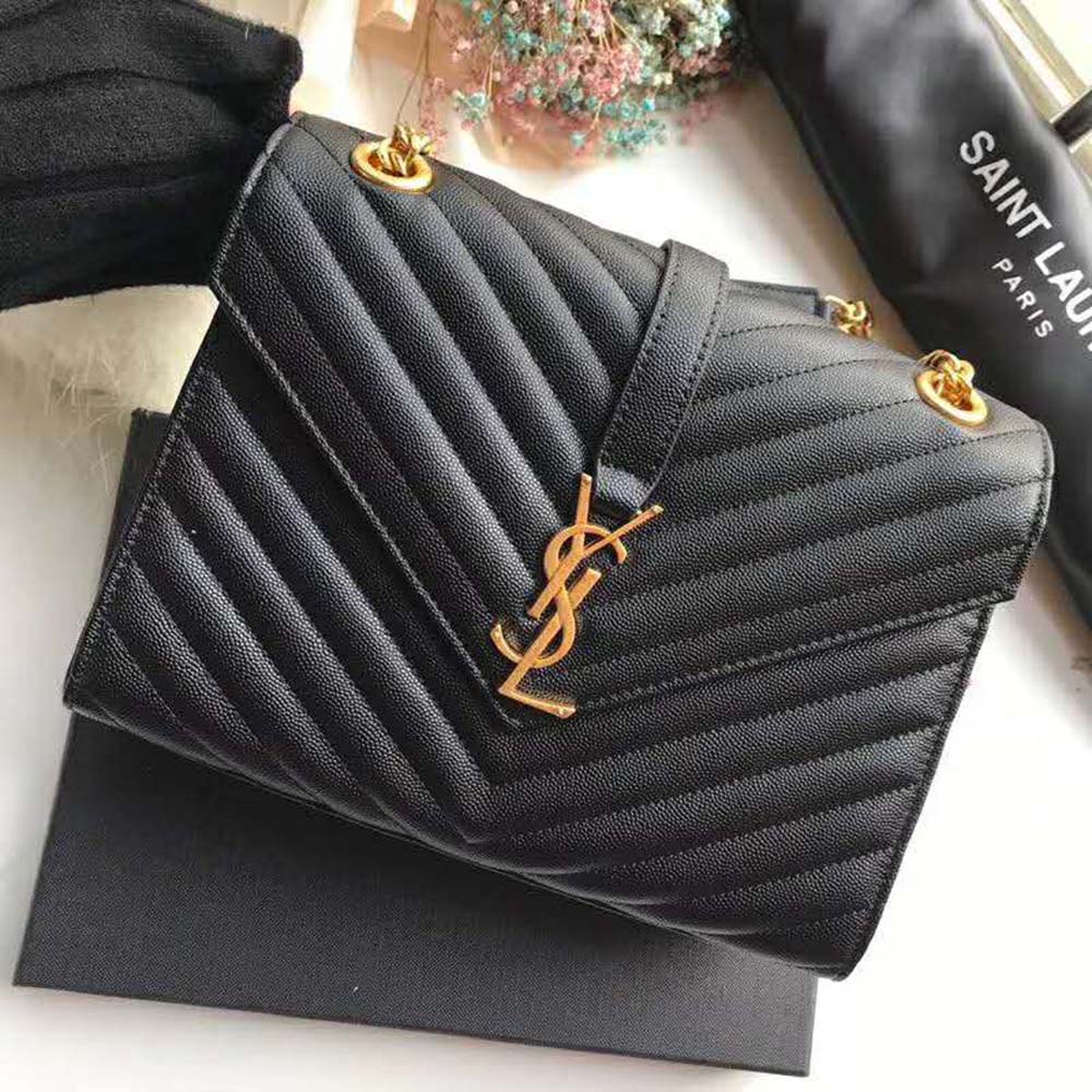 Close-up of gold YSL logo hardware on embossed black leather bag