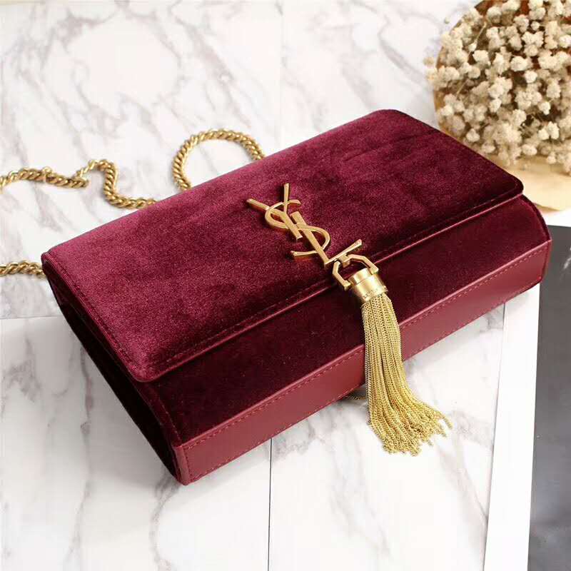 Close-up of gold YSL tassel on velvet maroon Saint Laurent bag