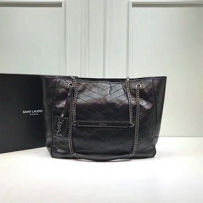 Close-up of gold YSL logo hardware on crinkled leather bag