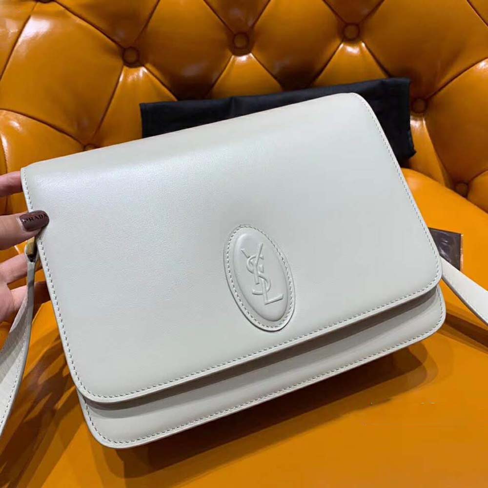 Close-up on gold-tone YSL logo hardware on smooth white bag