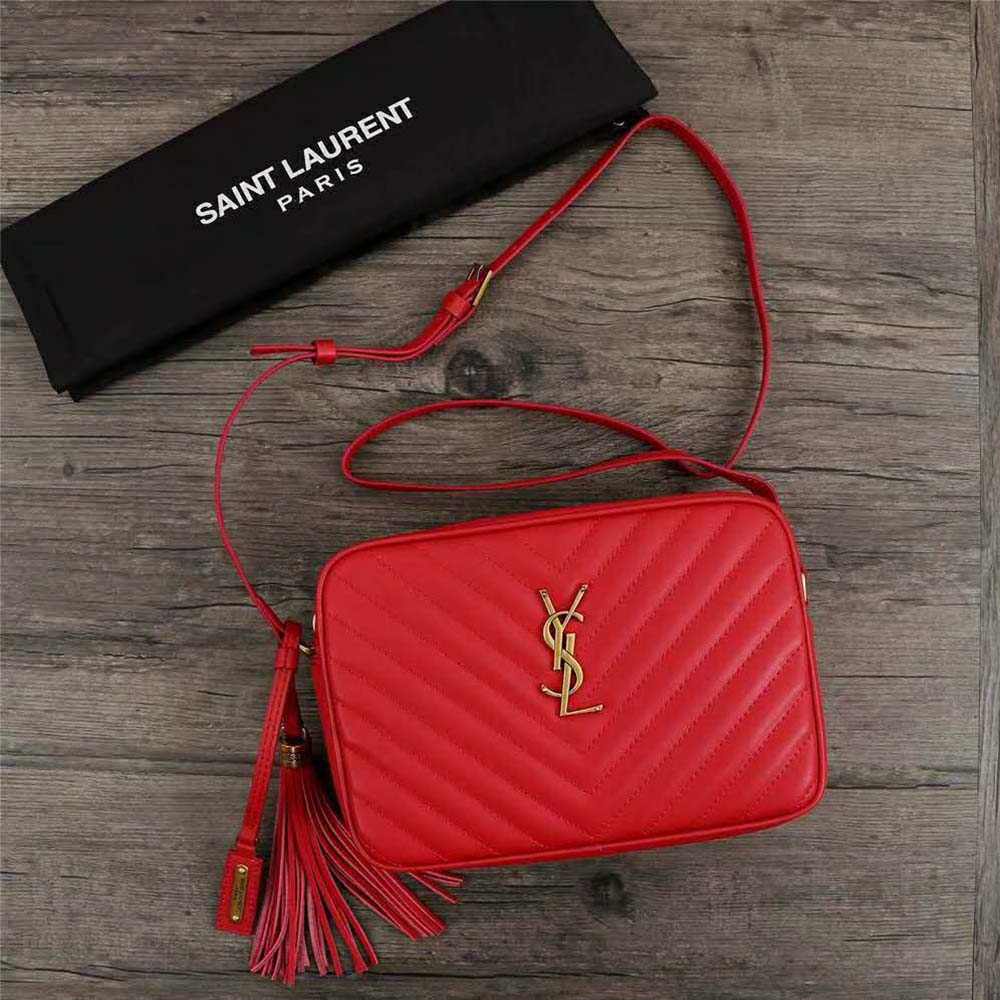 Close-up of gold YSL logo hardware on red camera bag