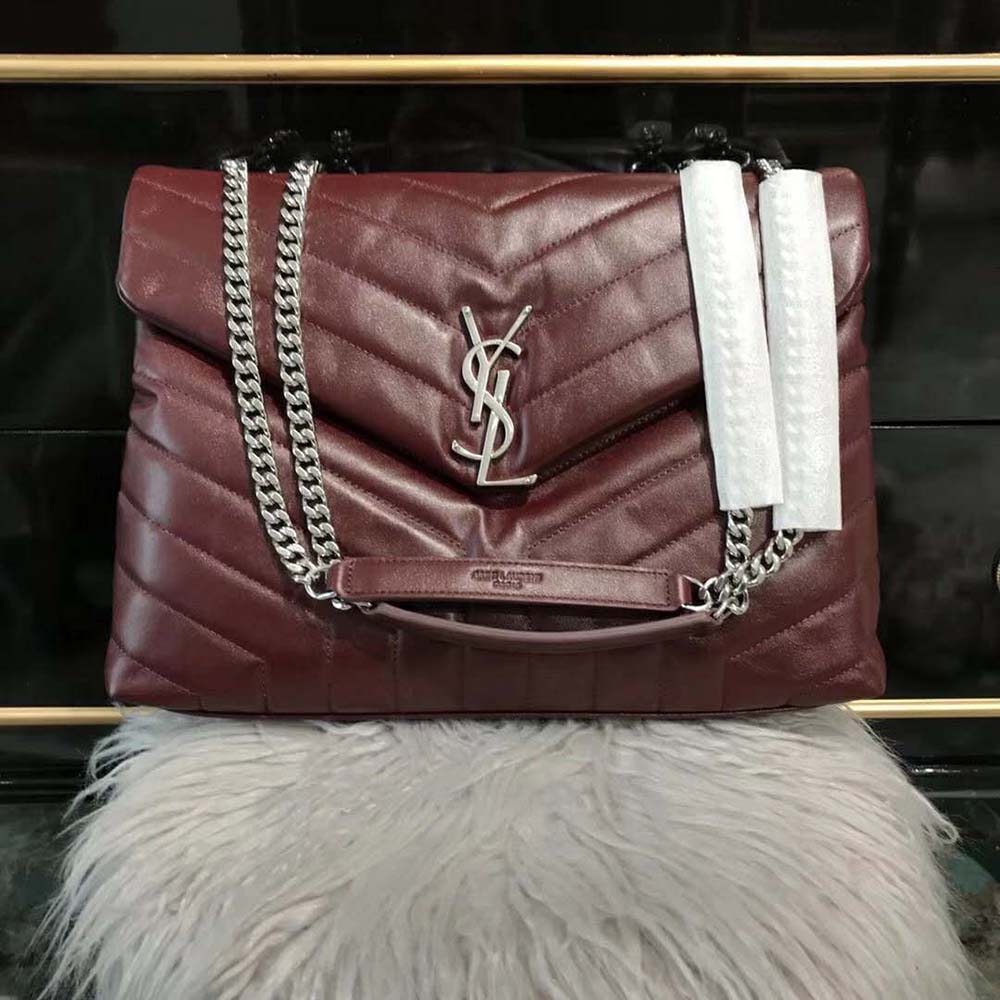 Close-up of gold YSL logo hardware on maroon leather bag