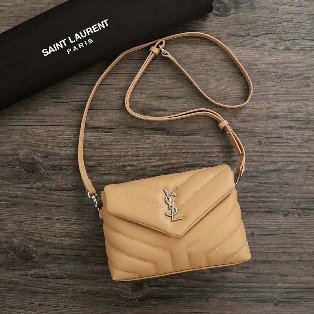 Close-up of gold YSL logo hardware on Sandy leather bag
