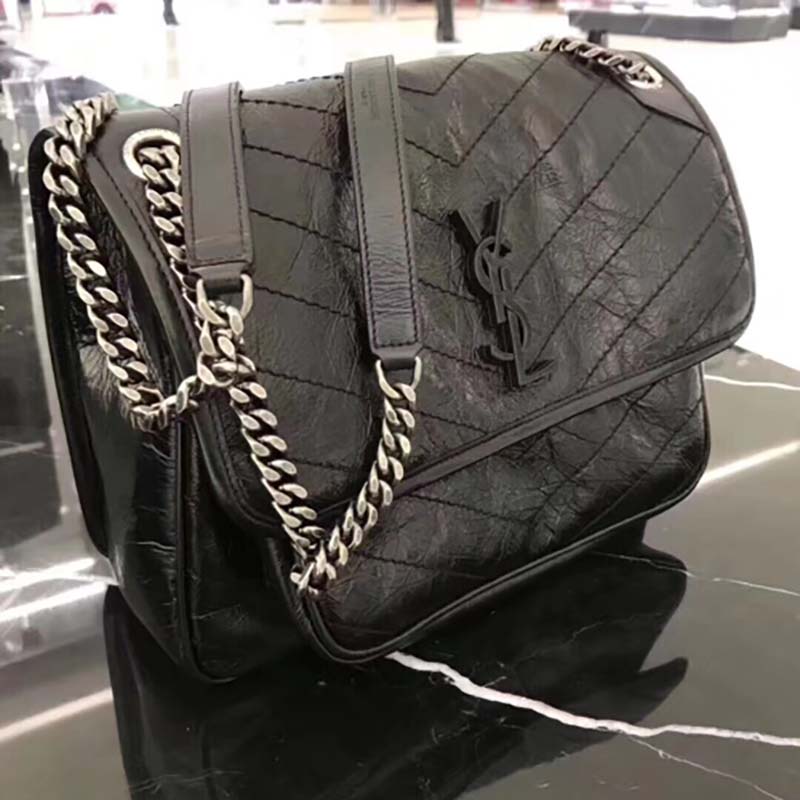 Close-up of gold YSL logo and chain on Saint Laurent Medium Niki bag