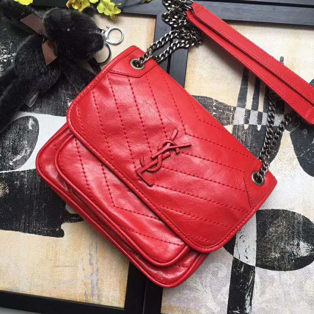 Close-up of gold YSL logo hardware on red vintage leather bag