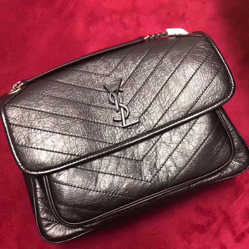 Close-up of antique gold YSL logo on vintage leather bag