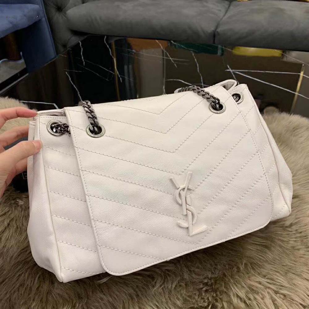 Close-up of gold YSL logo hardware on white vintage leather bag