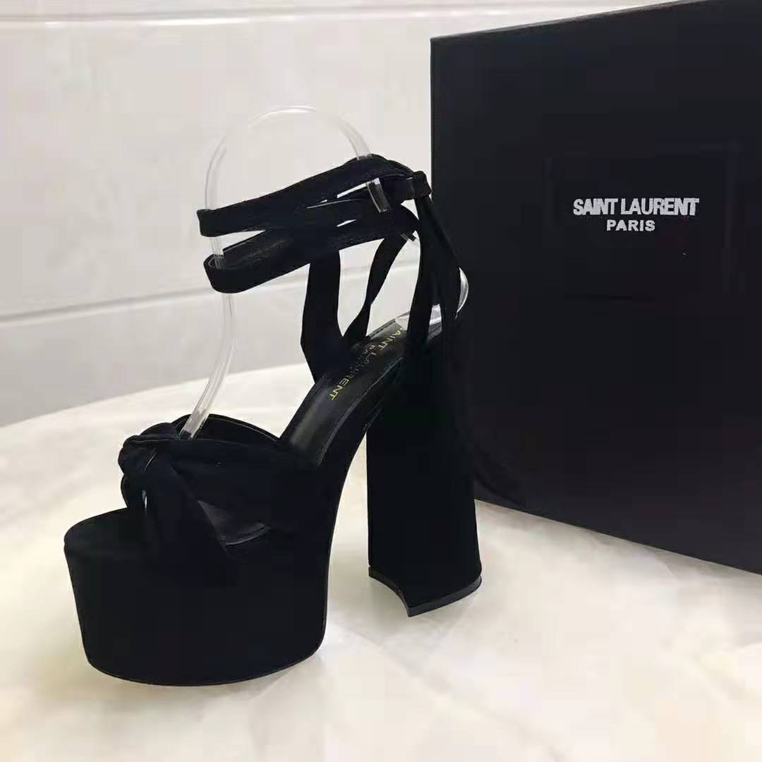 Close-up of gold YSL logo hardware on black suede sandals