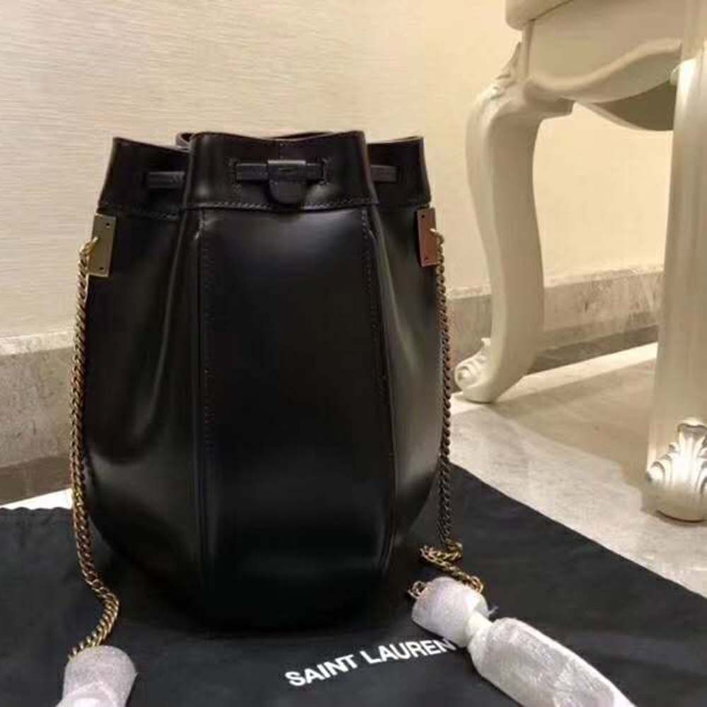 Close-up of gold-tone YSL logo hardware on black leather bag