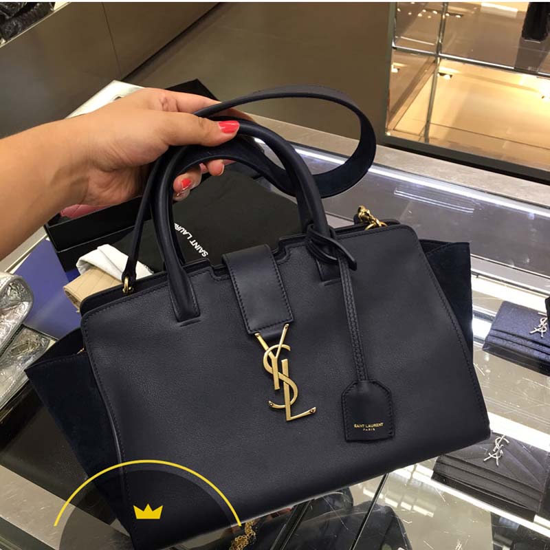 Close-up of gold YSL logo hardware on navy suede Downtown Cabas bag