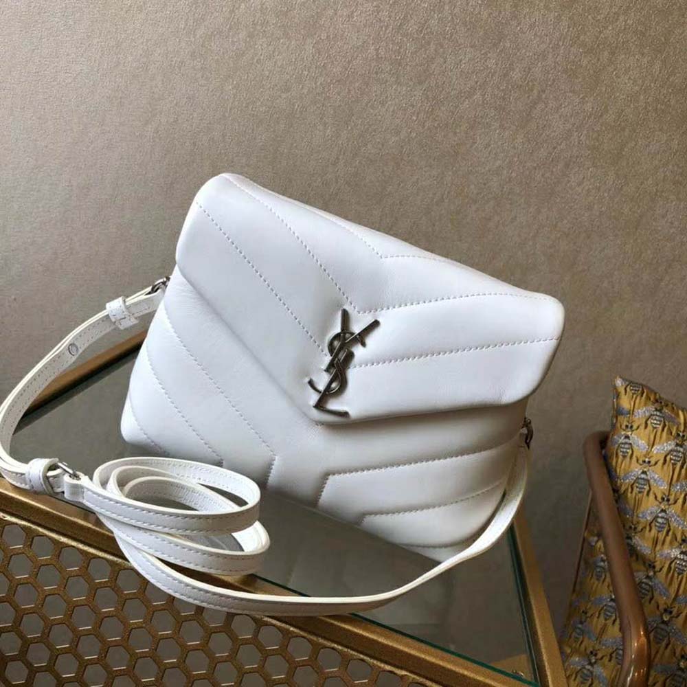 Close-up of gold-tone YSL hardware on white quilted leather bag