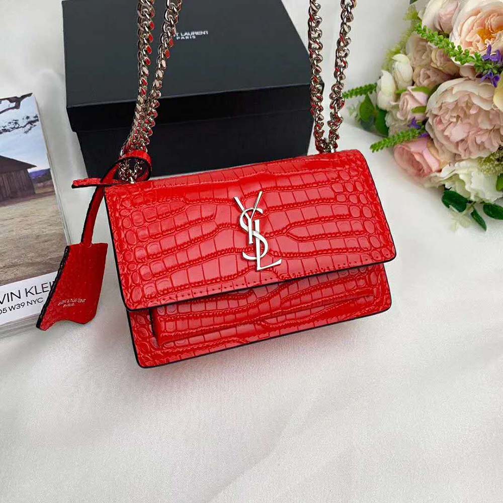 Close-up of gold YSL logo and glossy red crocodile texture