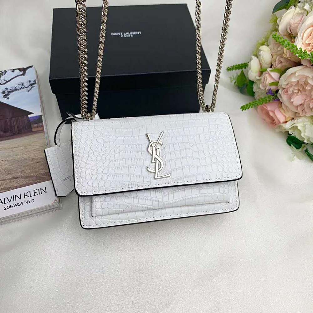 Close-up on signature gold YSL logo hardware on shiny-white bag