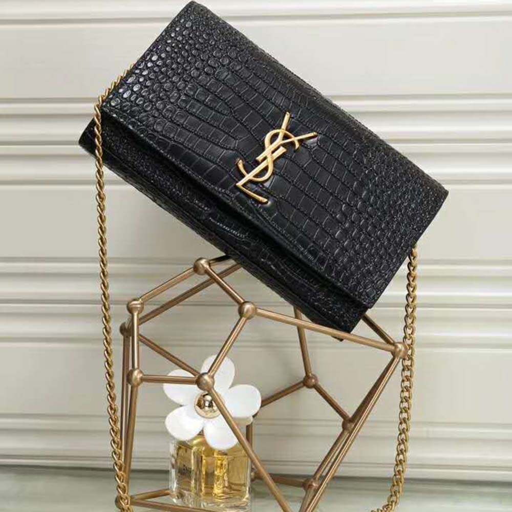 Close-up detail of YSL gold hardware on black crocodile-embossed leather