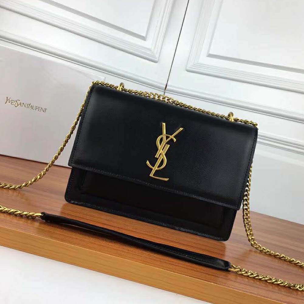 Close-up of gold YSL logo hardware on the black smooth leather bag