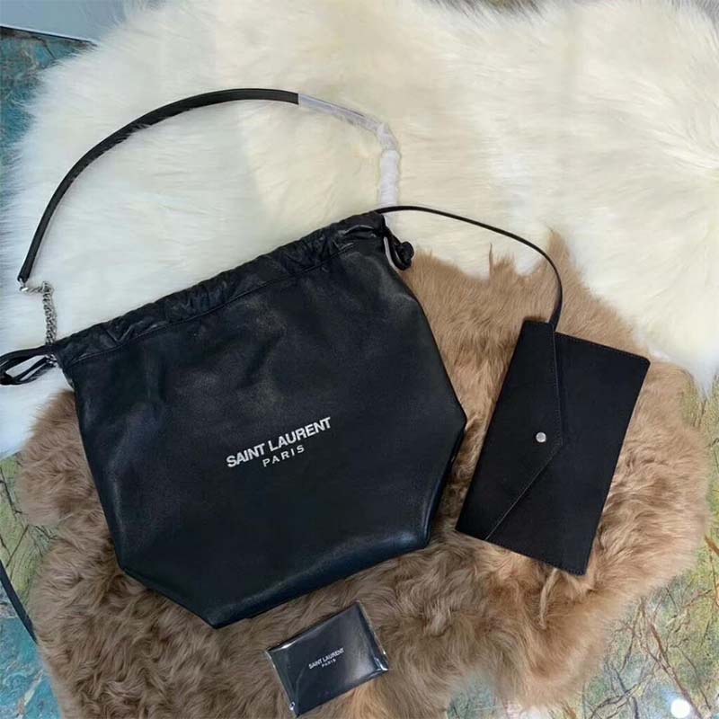 Close-up on gold-tone YSL logo hardware and smooth black leather texture