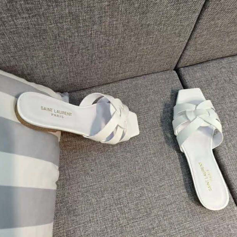Close-up of gold YSL logo hardware on white metallic leather sandal