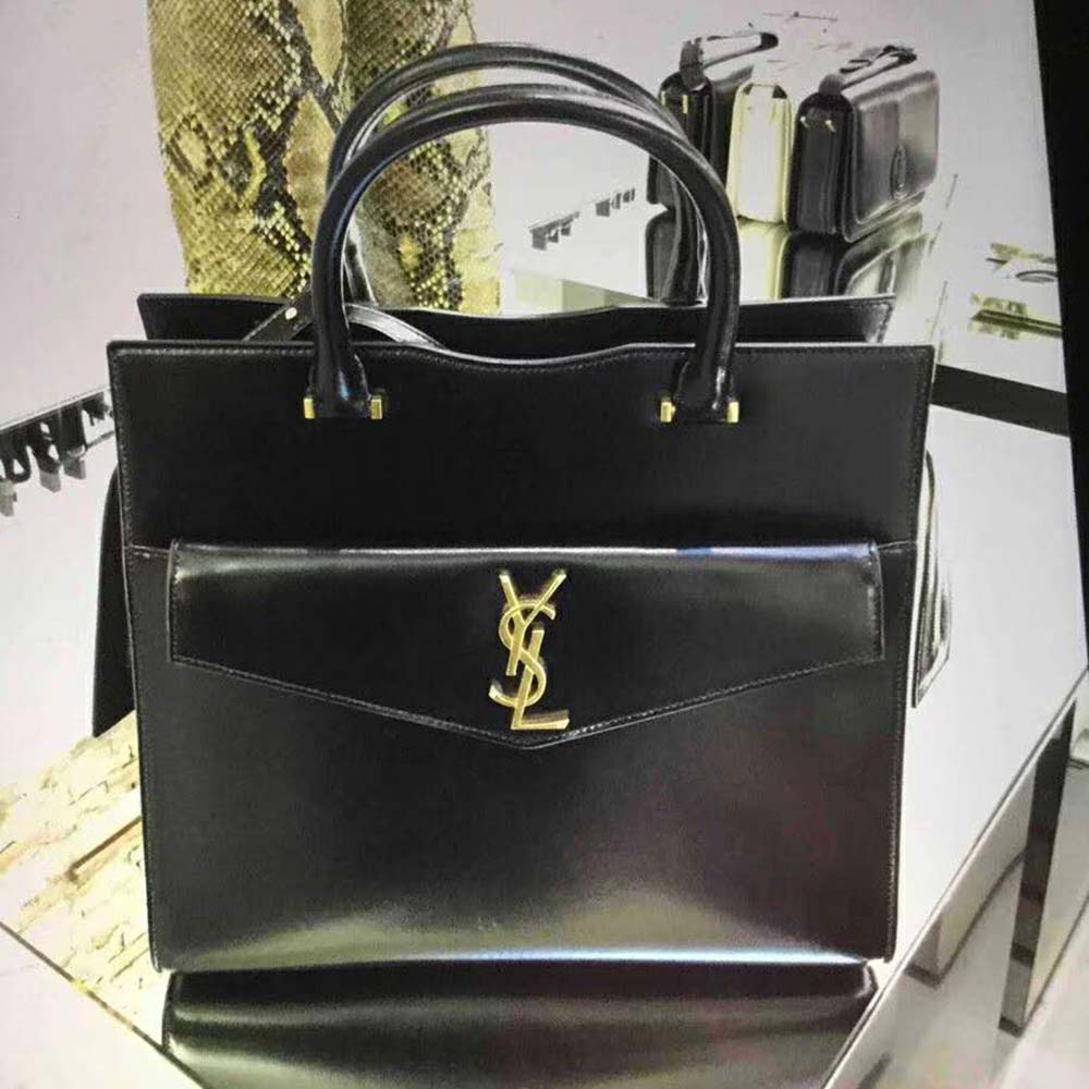 Close-up of gold YSL logo hardware on black leather Uptown Small Tote