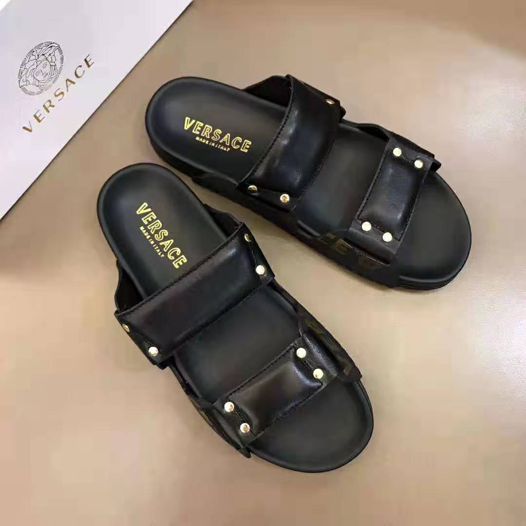Close-up of black leather and embossed Versace logo on sandals