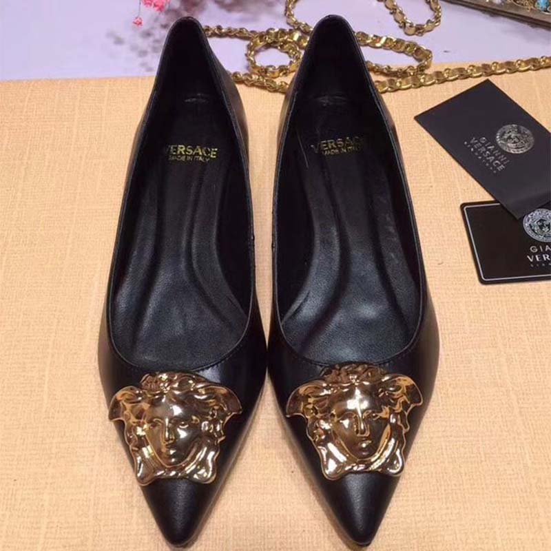 Close-up of black leather and Medusa emblem on Palazzo Ballerina Flats