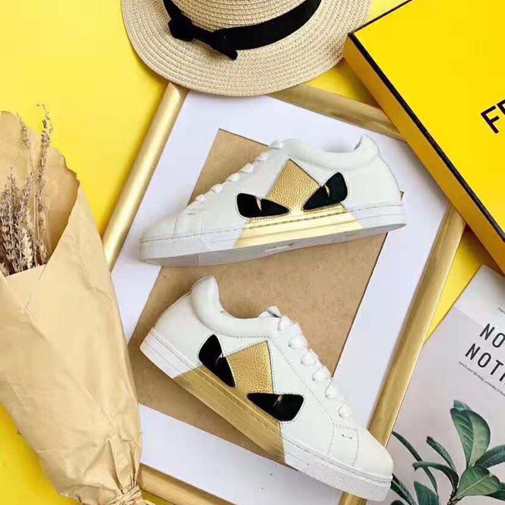 Close-up of lace-up closure and Fendi logo on white leather sneakers